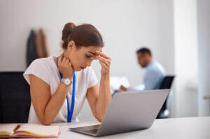 Mulher pensativa em frente ao notebook sentada em sua mesa